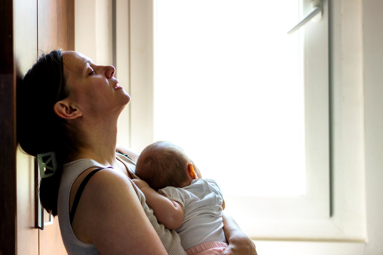 Tired concerned mother rocking sleeping baby.